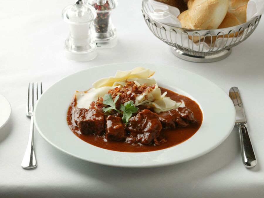 Ein Gulasch mit Nudeln in einem weißen Suppenteller